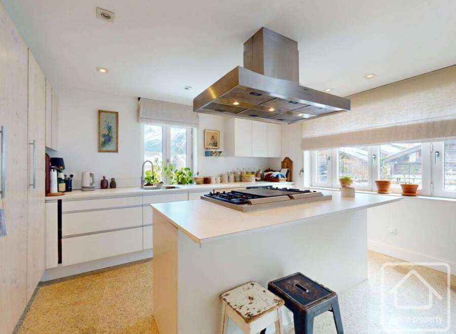 This stunning kitchen boasts a modern design with sleek white cabinetry and countertops, creating a bright and airy atmosphere.