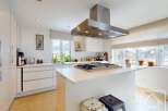 This stunning kitchen boasts a modern design with sleek white cabinetry and countertops, creating a bright and airy atmosphere.