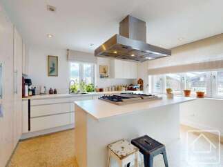 This stunning kitchen boasts a modern design with sleek white cabinetry and countertops, creating a bright and airy atmosphere.
