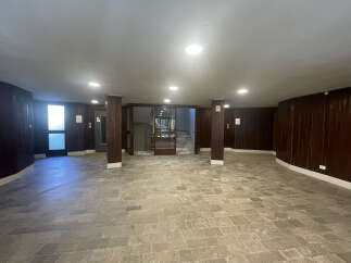 This spacious entryway boasts a unique design with dark wood paneling and a tiled floor, creating a warm and inviting atmosphere.