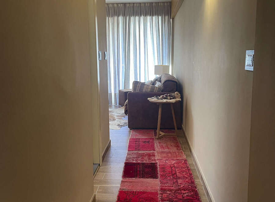 Step into luxury with this stunning property! The hallway features a vibrant red patchwork rug that adds a touch of warmth and character.