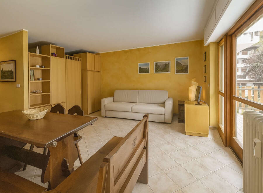 This charming property features a cozy living space with a comfortable sofa and a dining area with a wooden table.