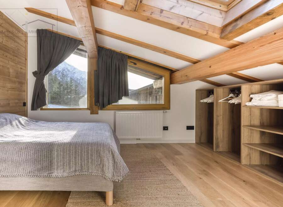 This cozy bedroom features a rustic wooden ceiling and walls, creating a warm and inviting atmosphere.