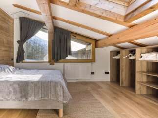 This cozy bedroom features a rustic wooden ceiling and walls, creating a warm and inviting atmosphere.