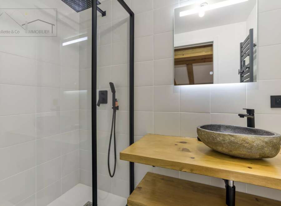 This modern bathroom boasts a sleek design with a walk-in shower and a stylish stone sink.
