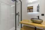 This modern bathroom boasts a sleek design with a walk-in shower and a stylish stone sink.
