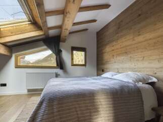 Experience the charm of this cozy bedroom featuring a rustic wooden headboard and exposed beams.
