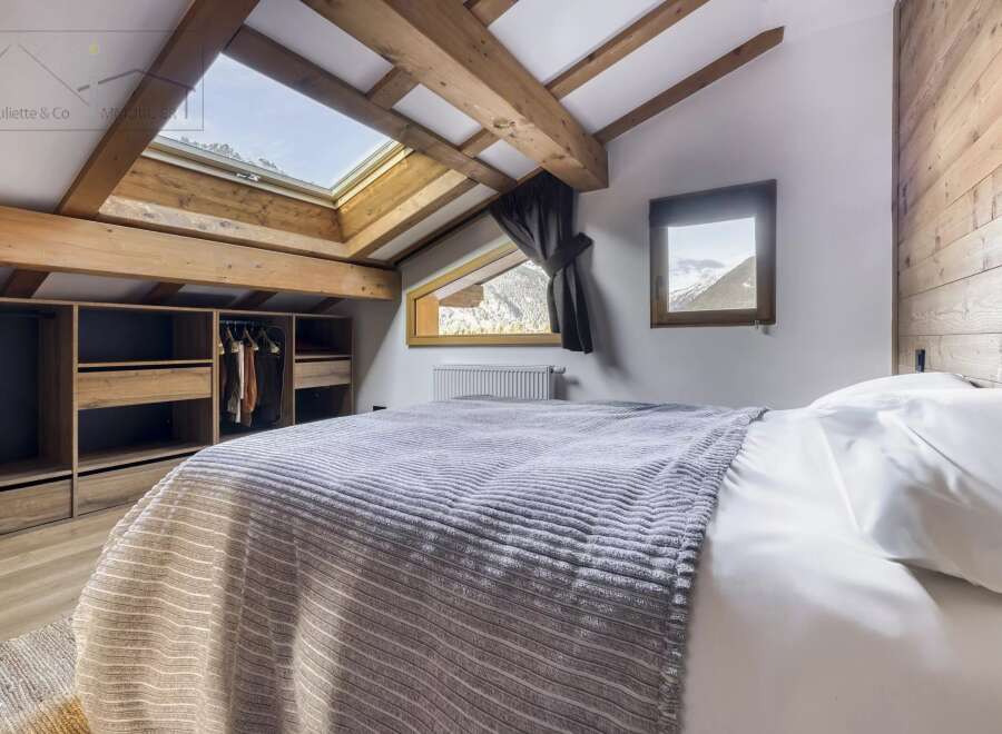 This charming bedroom features a cozy, inviting atmosphere with its wooden beams and natural light.