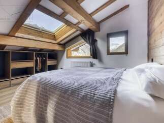 This charming bedroom features a cozy, inviting atmosphere with its wooden beams and natural light.