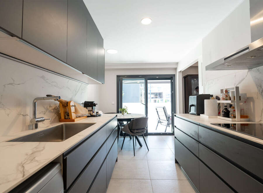 This modern kitchen boasts sleek, dark cabinetry and stunning marble countertops, creating a sophisticated and functional space.