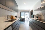This modern kitchen boasts sleek, dark cabinetry and stunning marble countertops, creating a sophisticated and functional space.