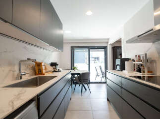 This modern kitchen boasts sleek, dark cabinetry and stunning marble countertops, creating a sophisticated and functional space.