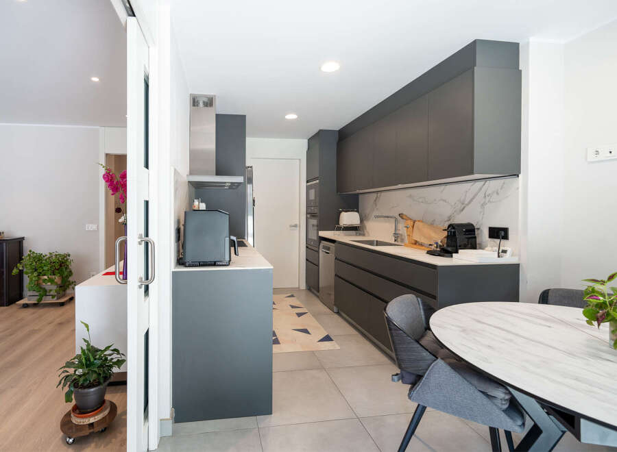 This modern kitchen boasts sleek gray cabinetry, a marble backsplash, and stainless steel appliances, creating a stylish and functional space.