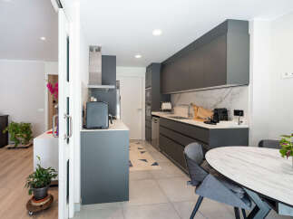 This modern kitchen boasts sleek gray cabinetry, a marble backsplash, and stainless steel appliances, creating a stylish and functional space.