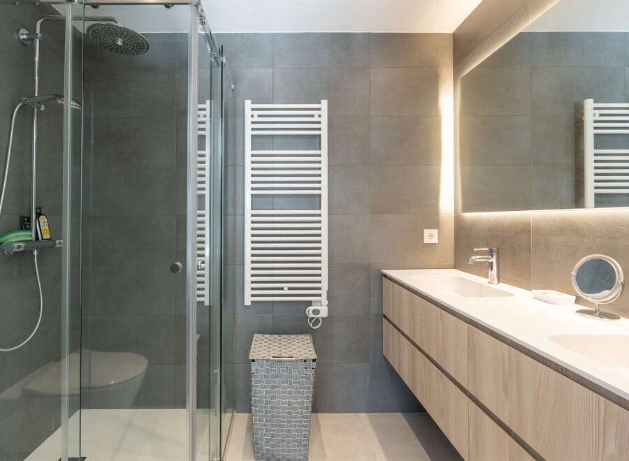 Step into a modern bathroom oasis! This stunning space features a sleek glass shower, a stylish vanity with ample storage, and a heated towel rack for added comfort.