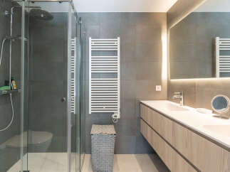 Step into a modern bathroom oasis! This stunning space features a sleek glass shower, a stylish vanity with ample storage, and a heated towel rack for added comfort.