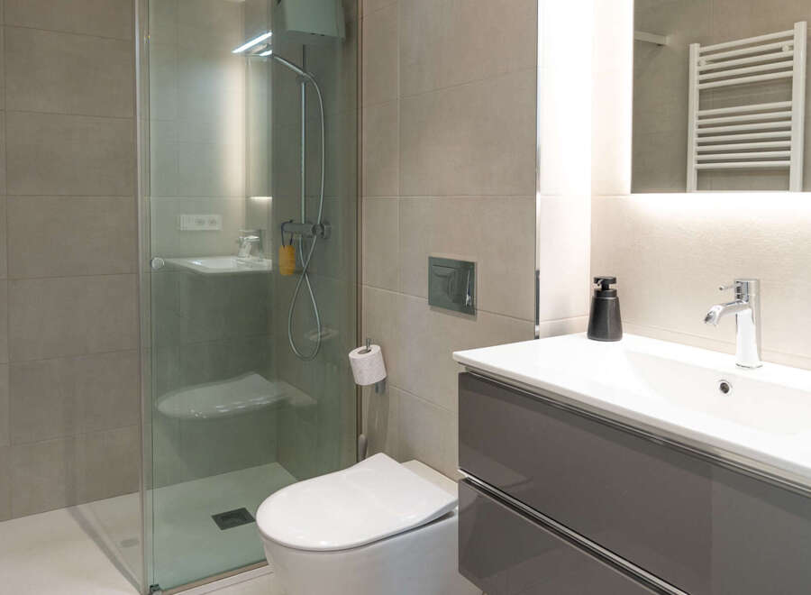 Step into a modern bathroom oasis! This stunning space features a sleek glass shower, a contemporary vanity with ample storage, and a stylish toilet.