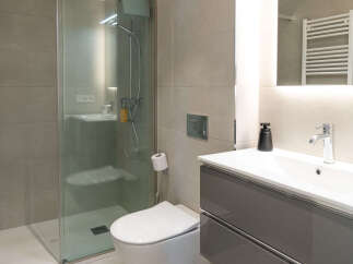 Step into a modern bathroom oasis! This stunning space features a sleek glass shower, a contemporary vanity with ample storage, and a stylish toilet.