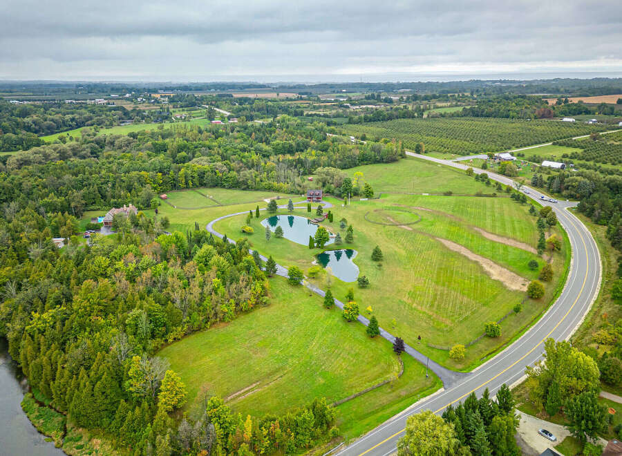 Discover a stunning rural property featuring a picturesque pond, lush greenery, and a charming house.