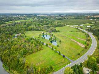 Discover a stunning rural property featuring a picturesque pond, lush greenery, and a charming house.