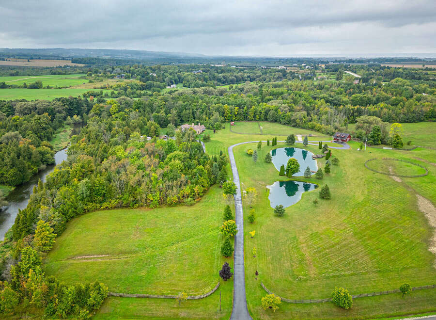Discover a stunning rural estate boasting lush greenery, serene ponds, and a charming red-roofed house.