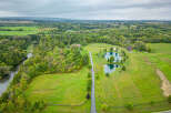 Discover a stunning rural estate boasting lush greenery, serene ponds, and a charming red-roofed house.