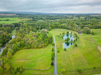 Discover a stunning rural estate boasting lush greenery, serene ponds, and a charming red-roofed house.