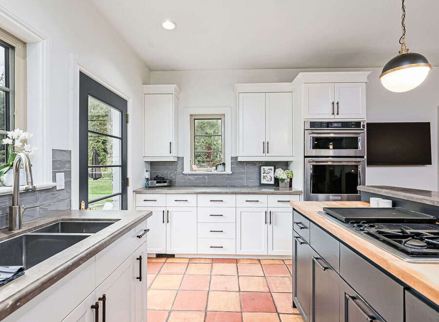 Step into this stunning kitchen, boasting a modern design with sleek white cabinetry and a contrasting dark island.