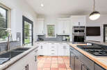 Step into this stunning kitchen, boasting a modern design with sleek white cabinetry and a contrasting dark island.
