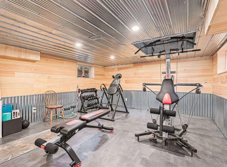 Step into your dream home gym! This space features a variety of exercise equipment, including a Bowflex machine, weight bench, and free weights.