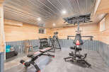 Step into your dream home gym! This space features a variety of exercise equipment, including a Bowflex machine, weight bench, and free weights.
