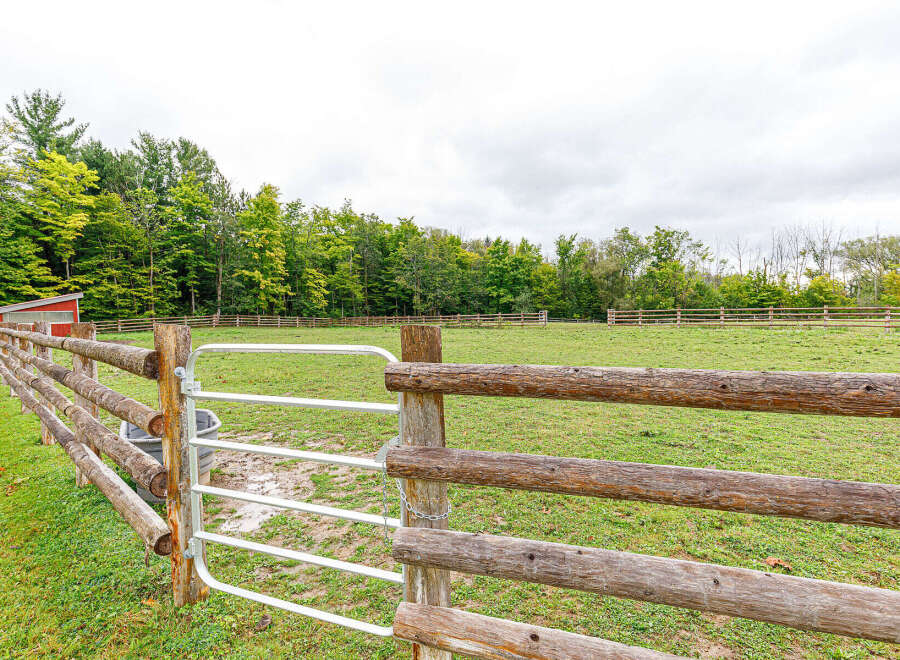 Discover the tranquility of this stunning property, featuring a beautifully crafted wooden fence that frames the lush green pasture.