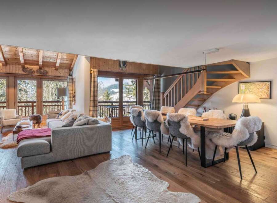 Experience luxury living in this stunning chalet, featuring a spacious living area with a cozy fireplace and large windows offering breathtaking mountain views.