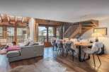 Experience luxury living in this stunning chalet, featuring a spacious living area with a cozy fireplace and large windows offering breathtaking mountain views.