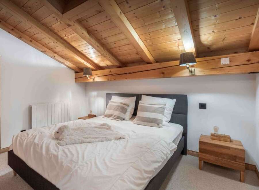 This cozy bedroom features a rustic wooden ceiling and a comfortable bed, perfect for a relaxing getaway.