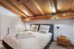This cozy bedroom features a rustic wooden ceiling and a comfortable bed, perfect for a relaxing getaway.