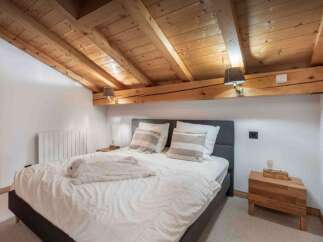 This cozy bedroom features a rustic wooden ceiling and a comfortable bed, perfect for a relaxing getaway.