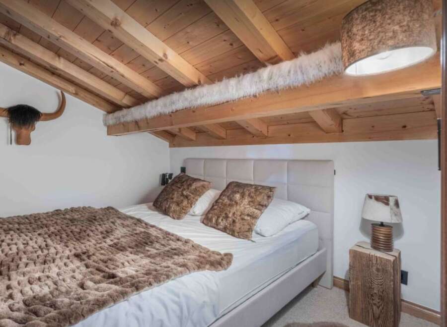 This cozy bedroom features a rustic design with wooden beams and a unique ceiling.