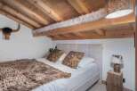 This cozy bedroom features a rustic design with wooden beams and a unique ceiling.
