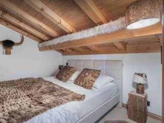 This cozy bedroom features a rustic design with wooden beams and a unique ceiling.