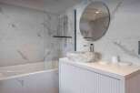 This stunning bathroom features a modern design with marble-like tiles and a sleek, white vanity.