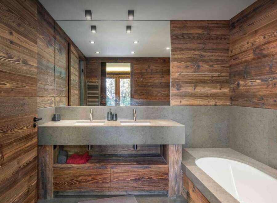This stunning bathroom features a rustic design with wood paneling and a modern concrete countertop.