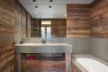 This stunning bathroom features a rustic design with wood paneling and a modern concrete countertop.