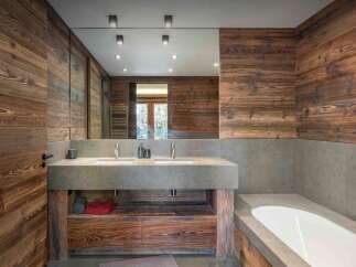 This stunning bathroom features a rustic design with wood paneling and a modern concrete countertop.