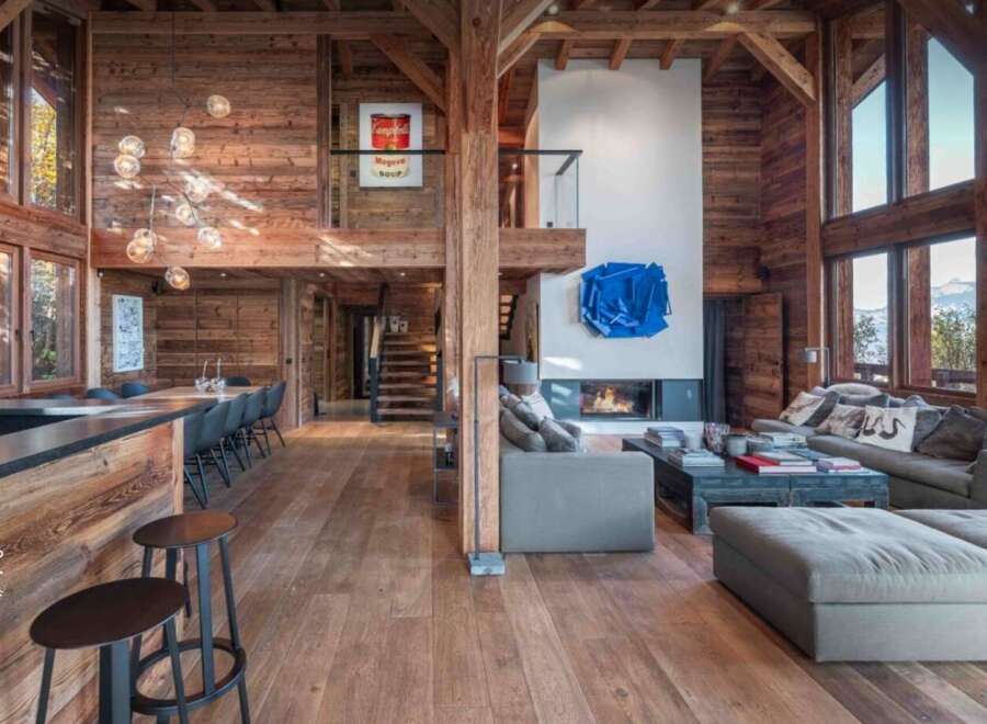 Experience luxury living in this stunning chalet-style home, boasting a warm and inviting interior with exposed wooden beams and flooring.