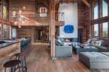 Experience luxury living in this stunning chalet-style home, boasting a warm and inviting interior with exposed wooden beams and flooring.