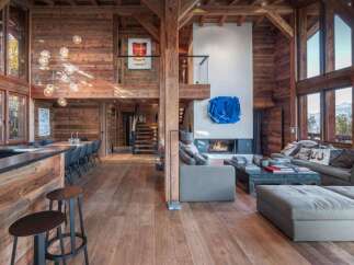 Experience luxury living in this stunning chalet-style home, boasting a warm and inviting interior with exposed wooden beams and flooring.