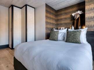 This luxurious bedroom showcases a blend of modern design and rustic charm, perfect for a relaxing retreat.
