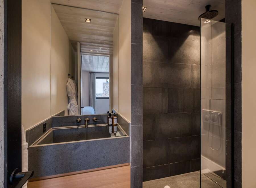 Experience luxury in this modern bathroom featuring a sleek concrete sink and a spacious walk-in shower.