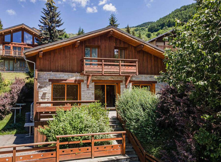 Experience mountain living in this charming wooden chalet, featuring a stone facade and multiple balconies offering scenic views.